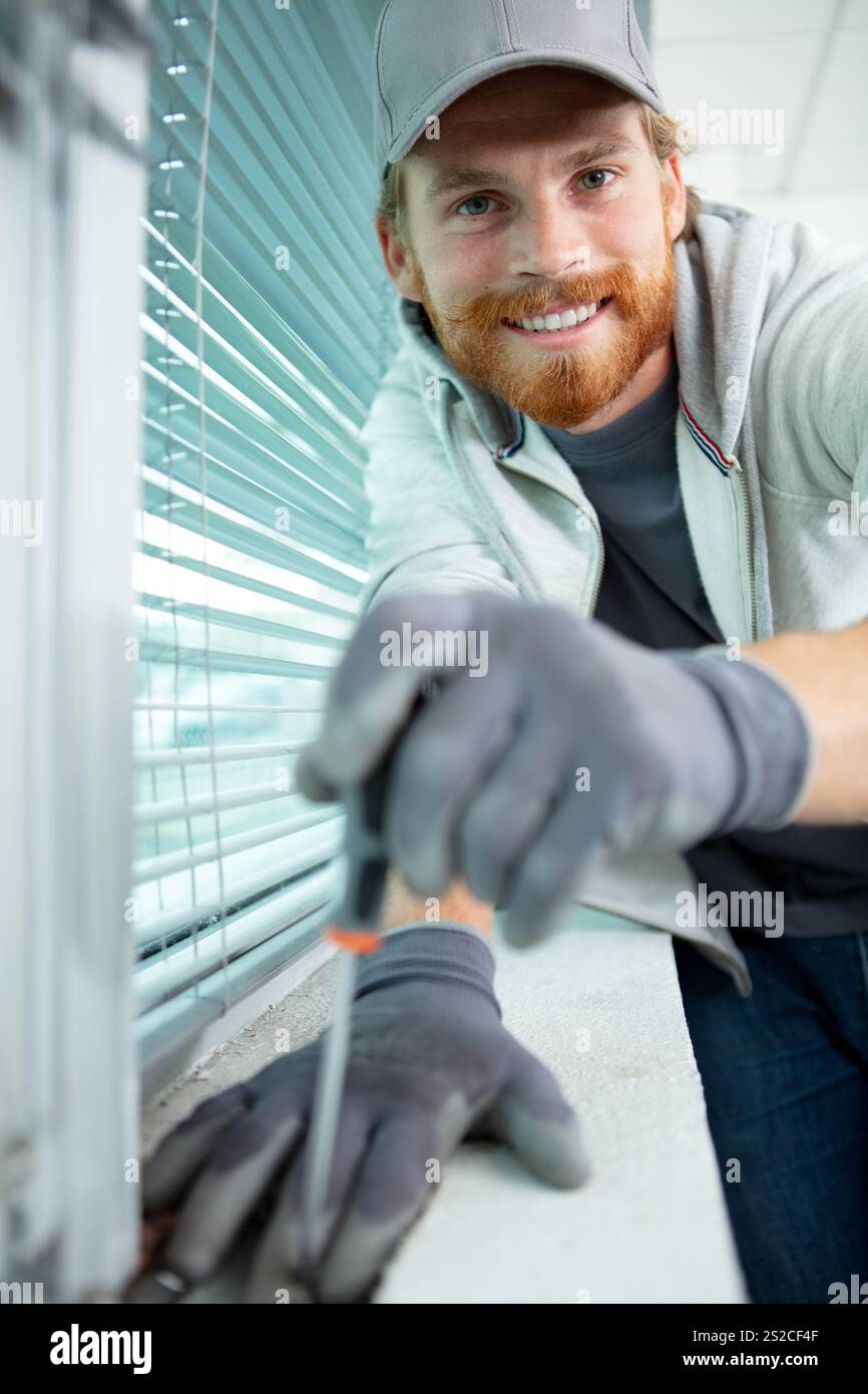 male contractor installing window blinds Stock Photo