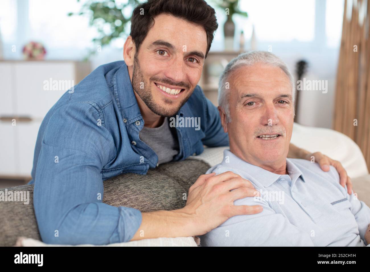 happy elderly father and son sit on couch Stock Photo