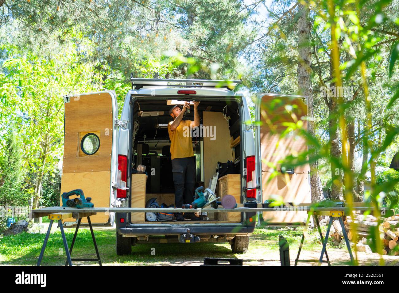 Carpenter working on campervan conversion, installing ceiling light in nature Stock Photo