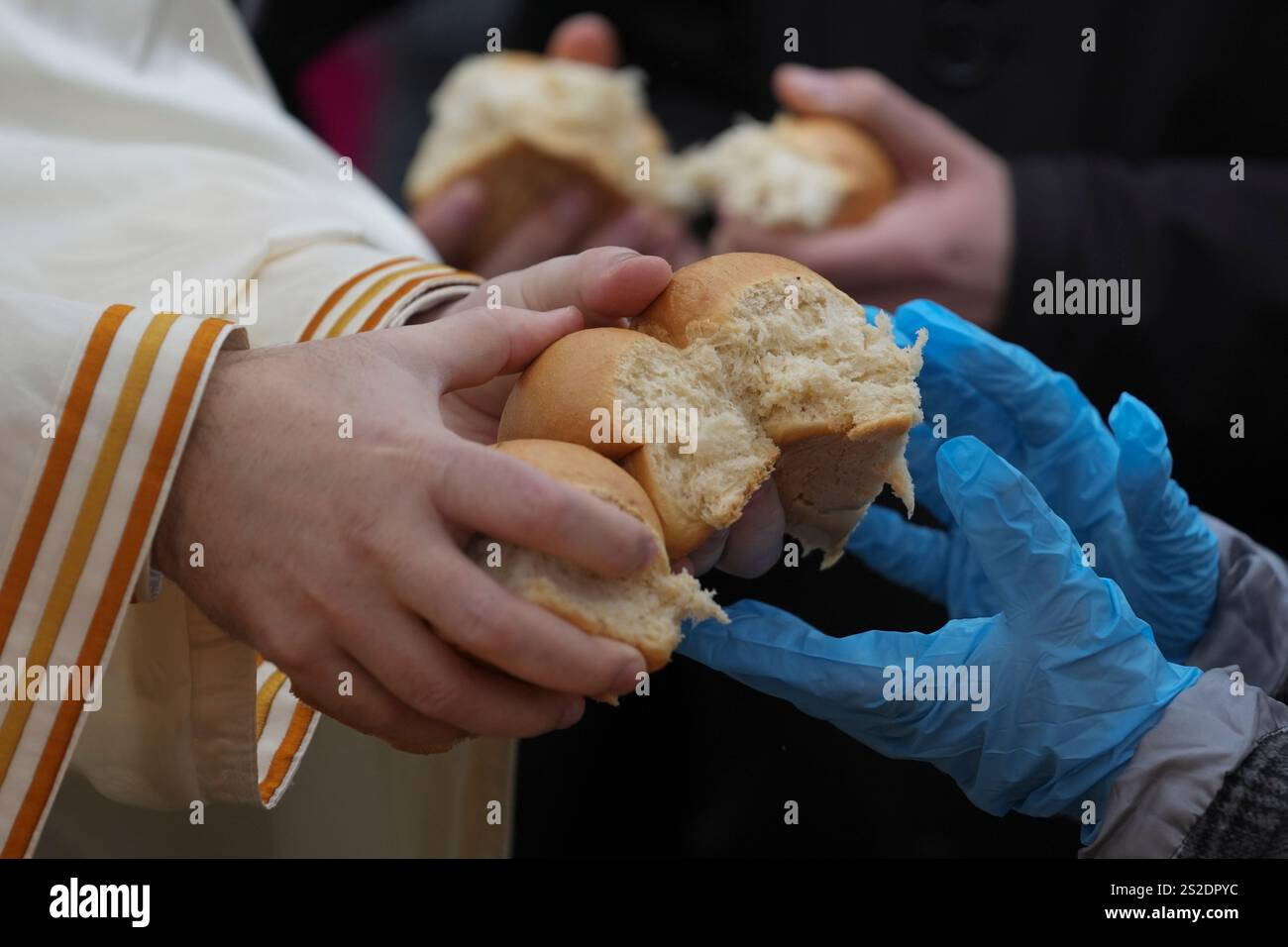 A priest, left, and child break traditional Christmas bread to mark the
