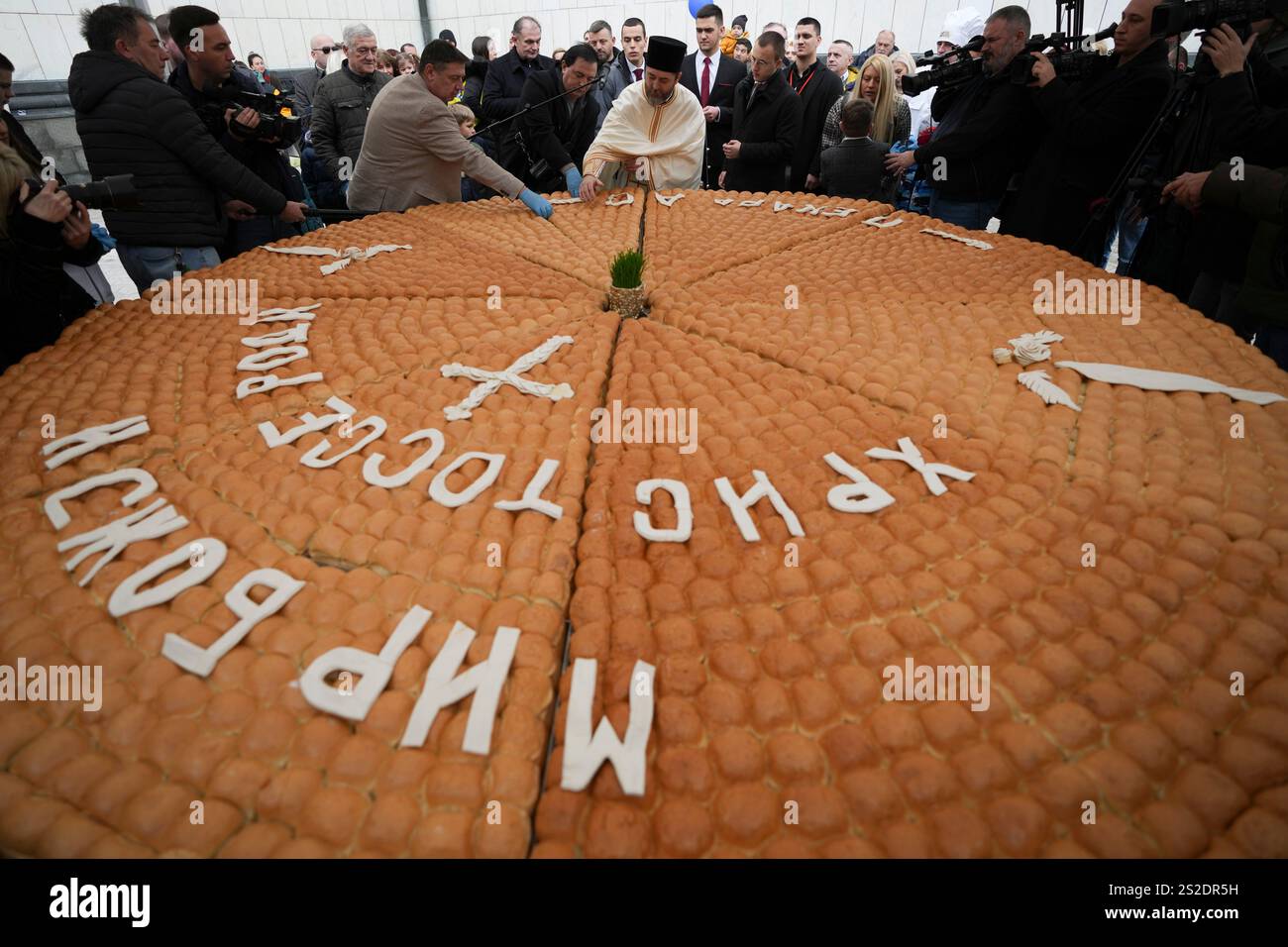 A priest, center, breaks traditional Christmas bread to mark the