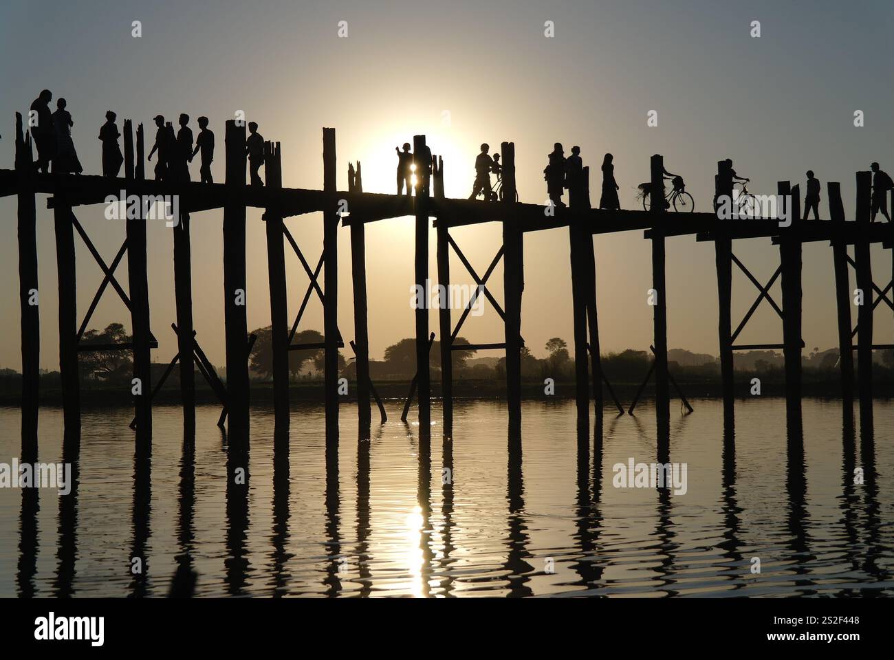 Silhouettes of people walking across the iconic U Bein Bridge, a ...