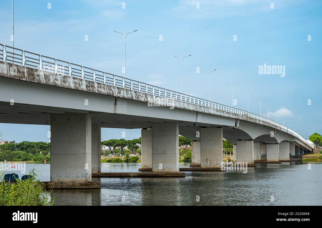 Overpass bridge. Old concrete bridge over a large river. Green trees on the shore. Communal bridge in the city Danang across the River. Automotive bri Stock Photo