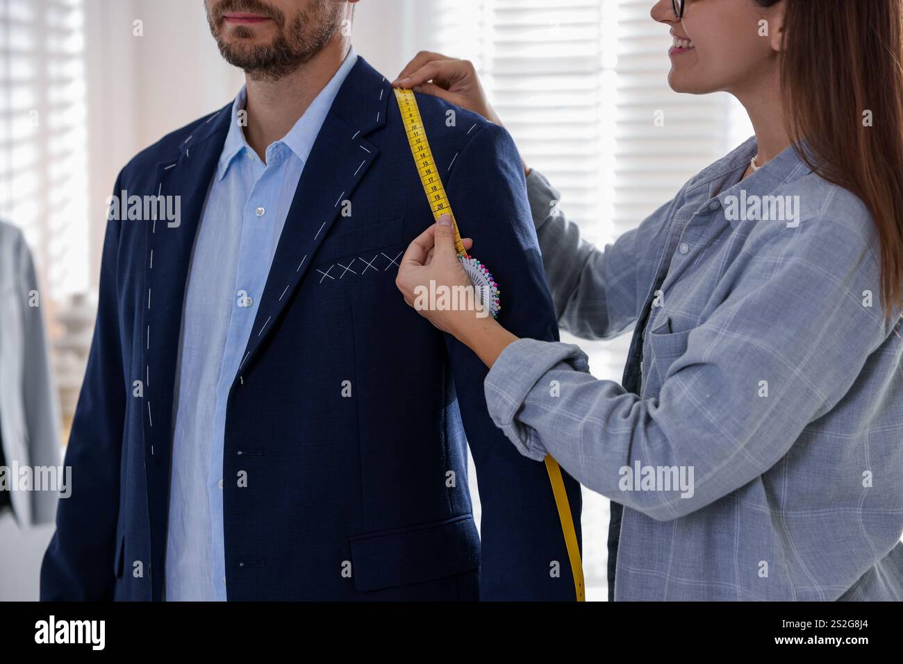 Tailor measuring jacket on man during fitting in atelier, closeup Stock Photo