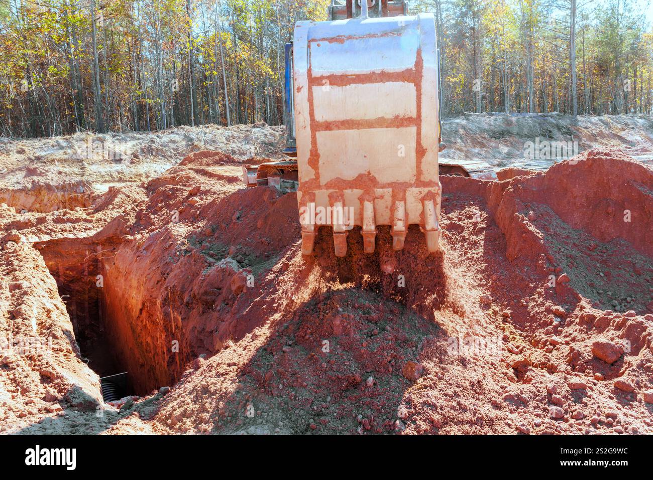 Heavy machinery removes soil in construction site, revealing deep ...