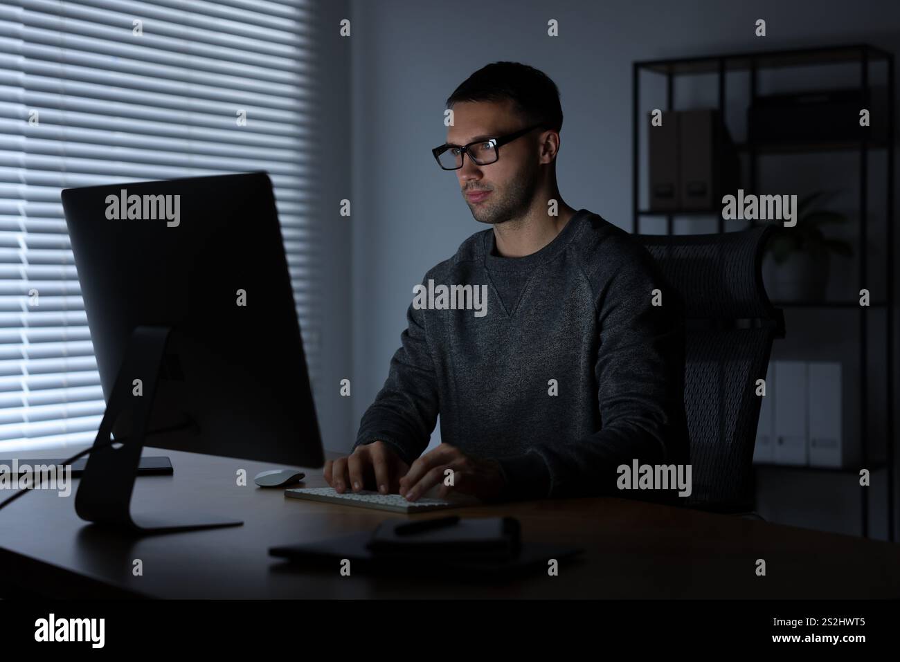 Programmer working on computer indoors at night Stock Photo