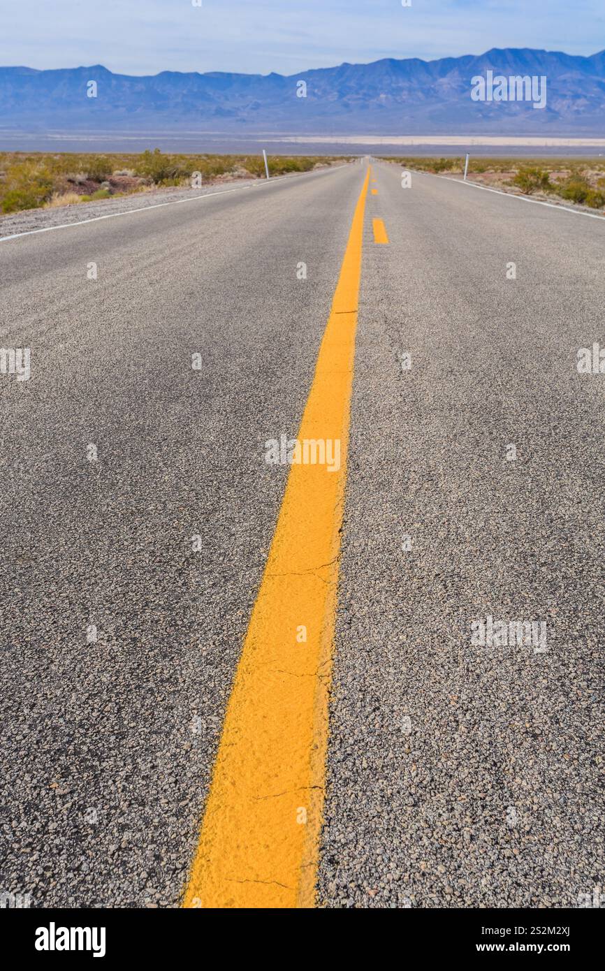 A long road with a yellow line down the middle. The road is empty and ...