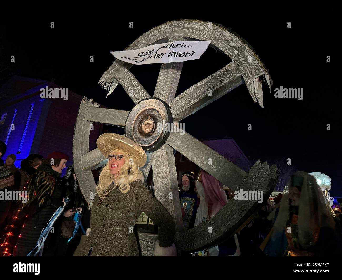 A marcher in the Joan of Arc parade carries a wheel symbolizing the
