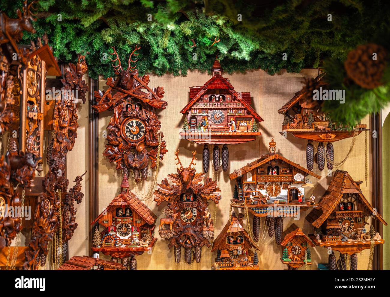 Rothenburg ob der Tauber, Germany - August 8, 2024: A collection of intricately designed wooden cuckoo clocks displayed on a wall, featuring various s Stock Photo