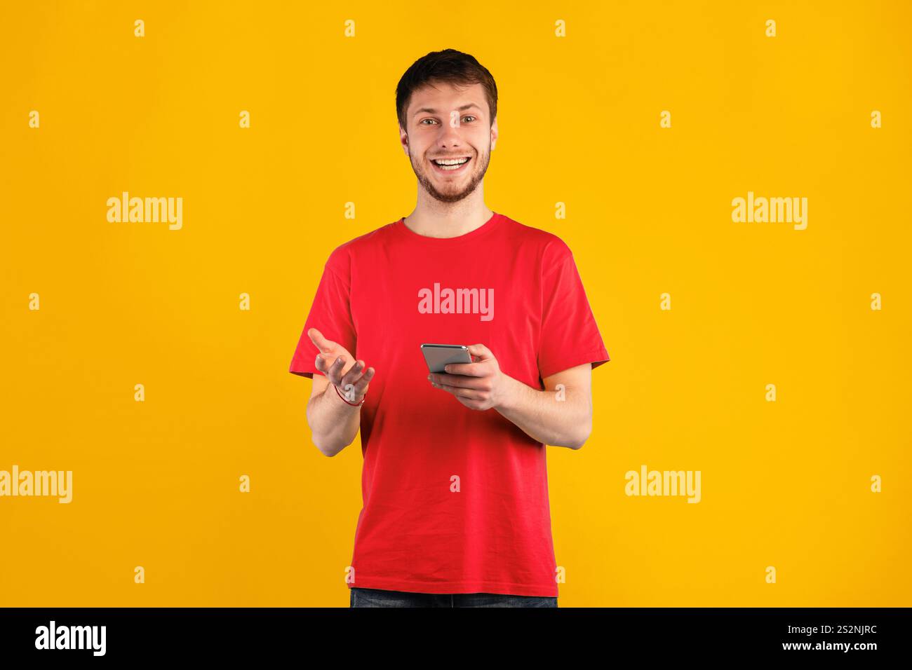 Smiling young man using mobile phone at studio Stock Photo