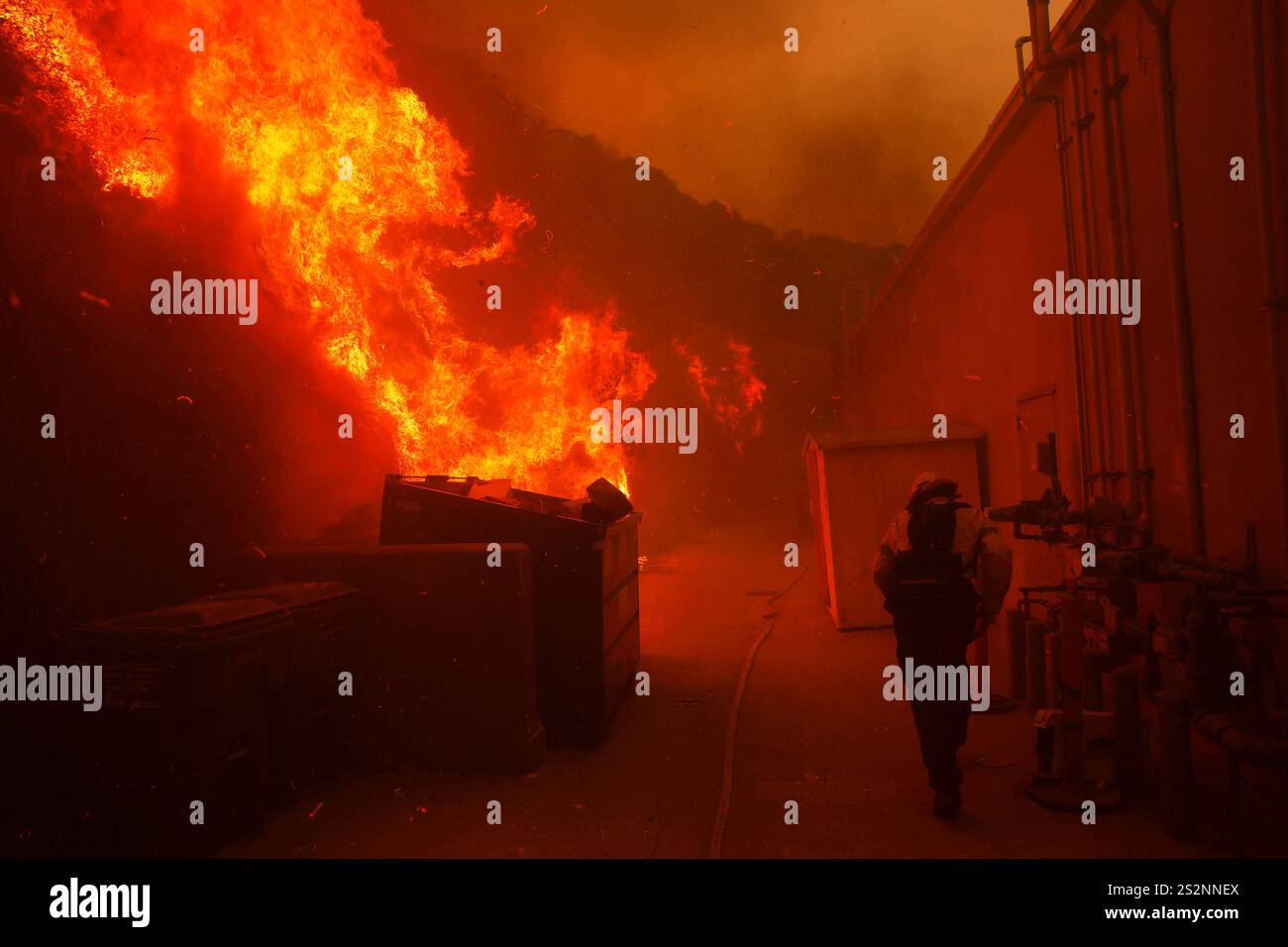 A firefighter protects a structure from the advancing Palisades Fire in