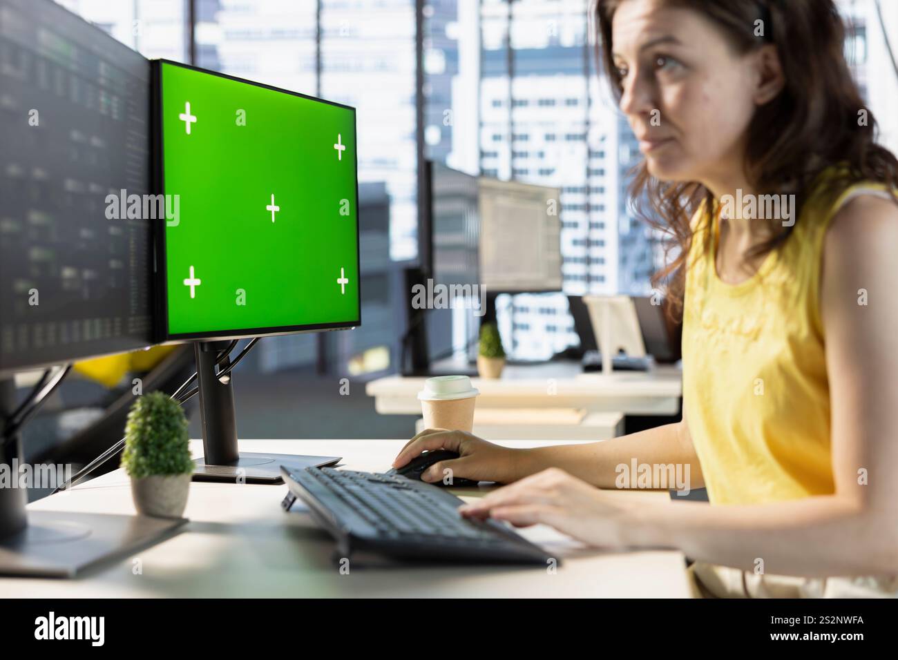 Woman testing and deploying machine learning programs and systems on isolated screen PC, solving tasks. Software engineer checking code on chroma key PC, sitting at desk in office Stock Photo