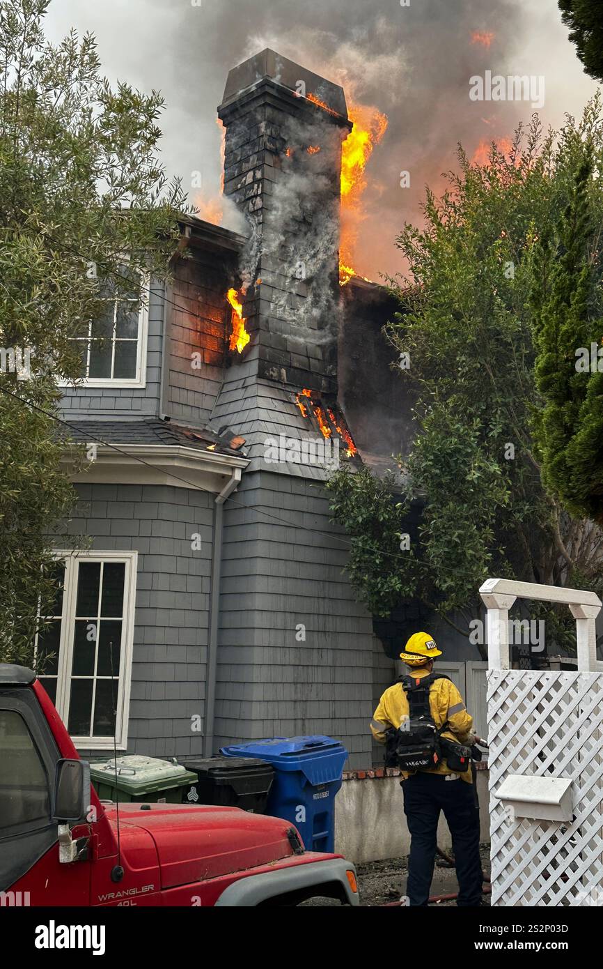 A structure burns as firefighters battle the Palisades Fire in the