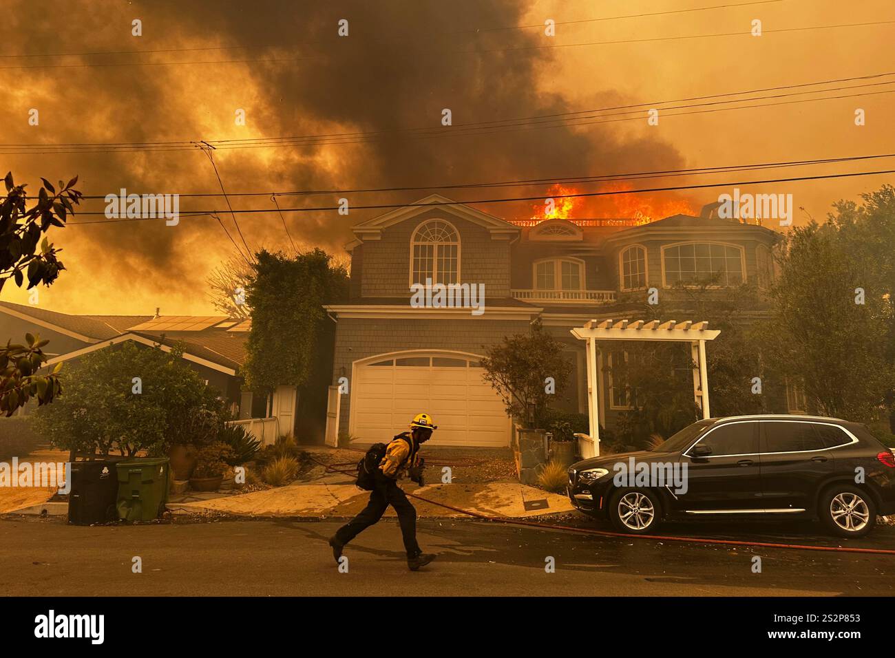 A residence burns as a firefighter battles the Palisades Fire in the