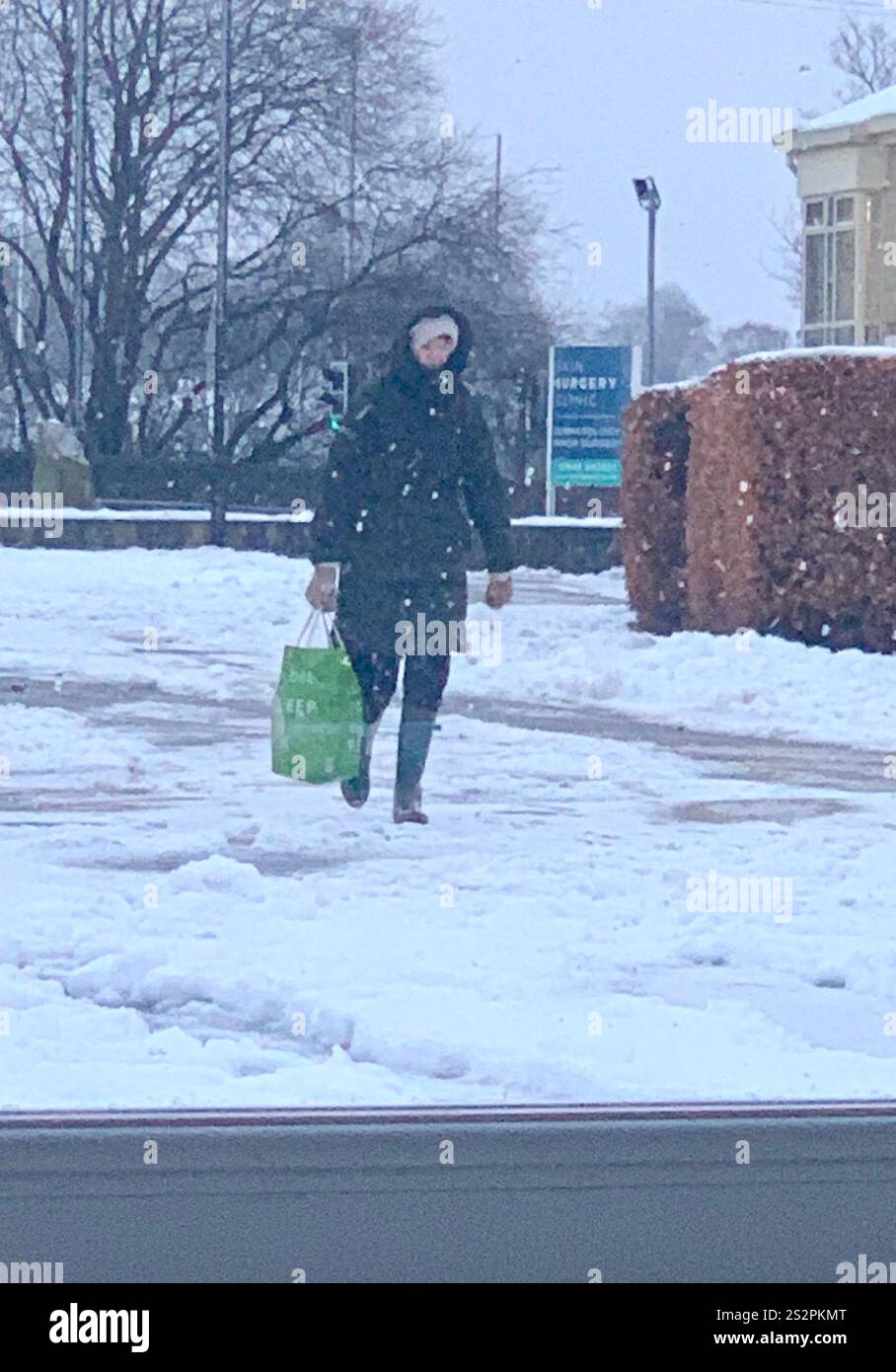 Lady walking in the Snow weather cold wet ice icy ground covered hat coat gloves boots wearing warm cold place sky grey snowing home walk walking - Smartphone Captured Stock Image