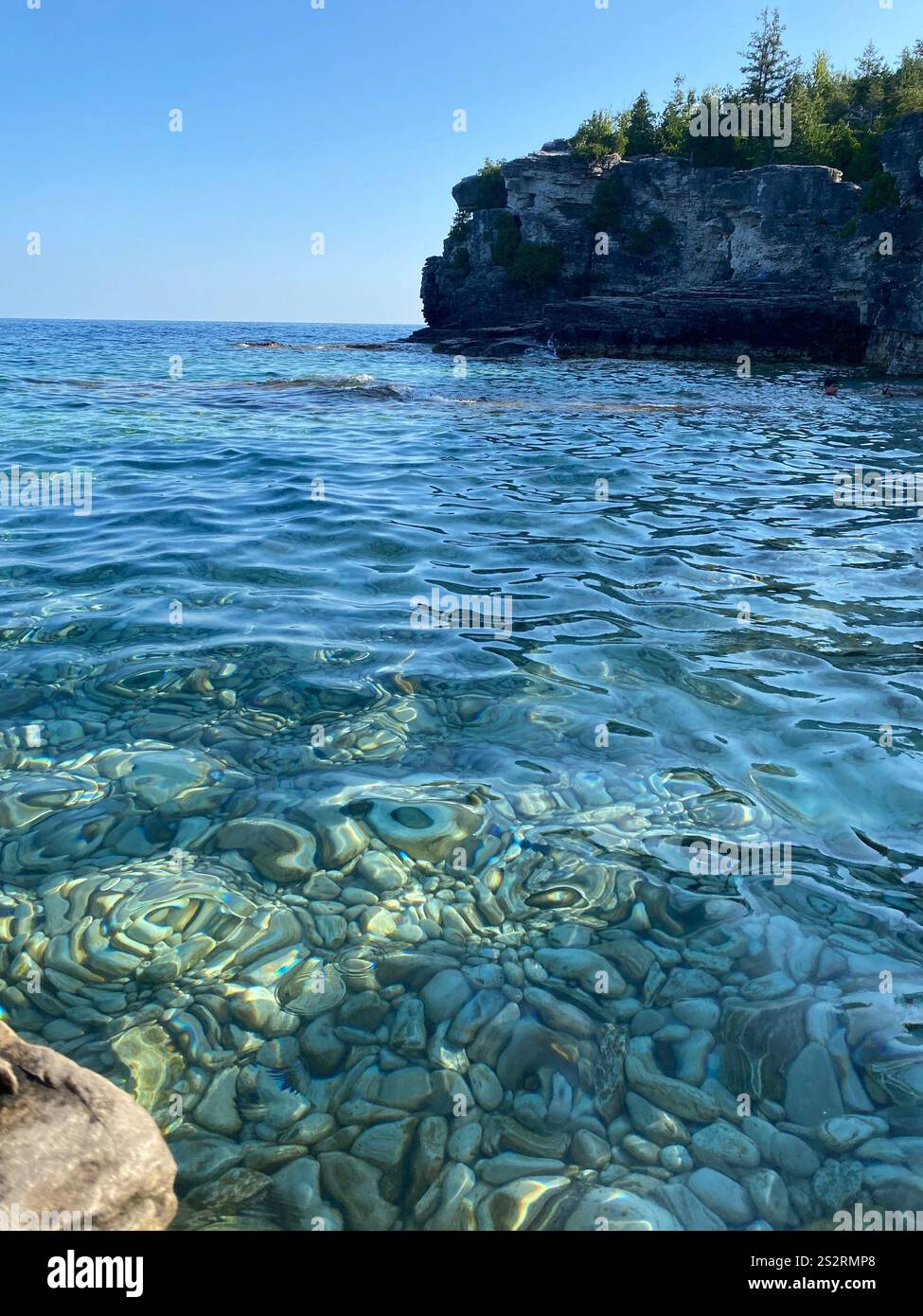 Crystal-clear turquoise water with rocky shoreline on the Bruce Peninsula, Ontario, Canada. - Smartphone Captured Stock Image