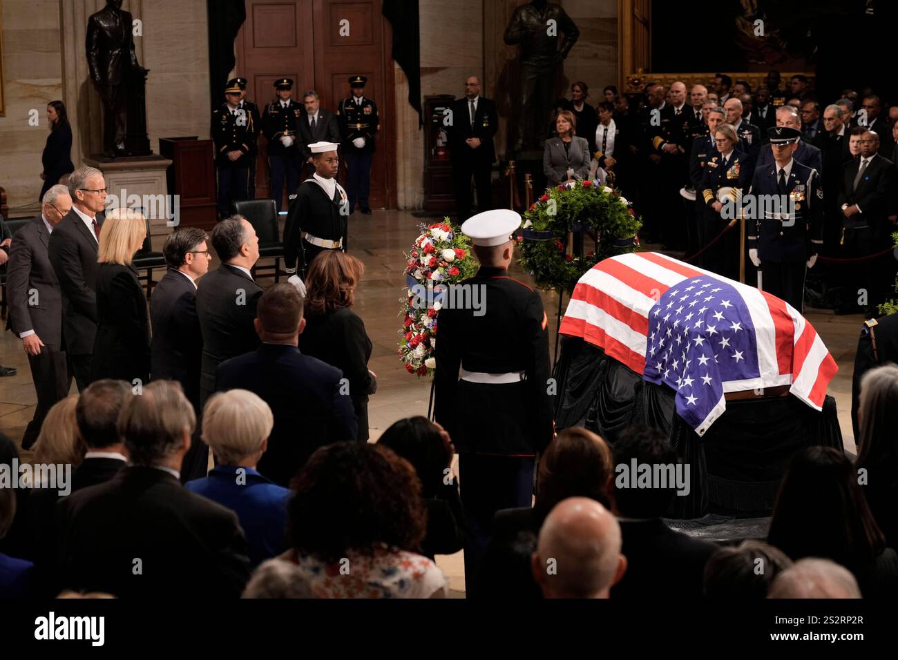 United States Senate Minority Leader Chuck Schumer (Democrat of New York), from left, United States Senate Majority Leader John Thune (Republican of South Dakota), and his wife Kimberley Thune, Speaker of the US House of Representatives Mike Johnson (Republican of Louisiana), second gentleman Doug Emhoff and US Vice President Kamala Harris look on as the flag-draped casket of former President Jimmy Carter lies in state in the Capitol, Tuesday, Jan. 7, 2025, in Washington. Carter died Dec. 29 at the age of 100. Credit: J. Scott Applewhite/Pool via CNP Stock Photo