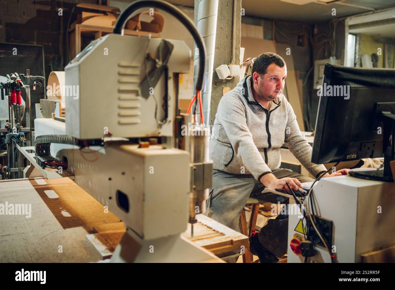 Portrait of an experienced worker changing tool setup of CNC machine ...