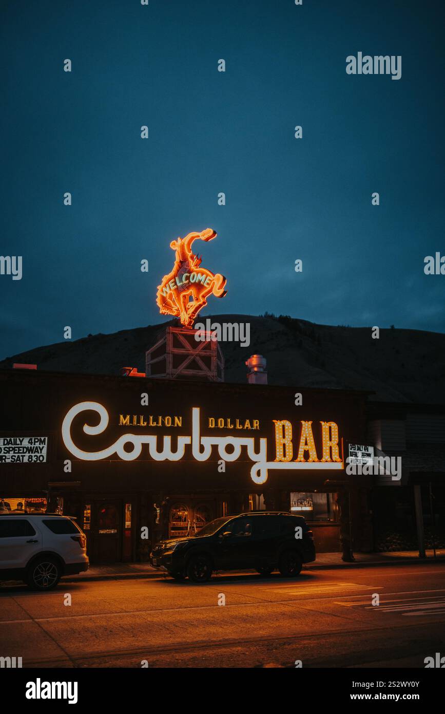 Illuminated neon signs of the iconic Million Dollar Cowboy Bar light up the night life in Jackson Hole Wyoming,capturing the essence of Western life. Stock Photo