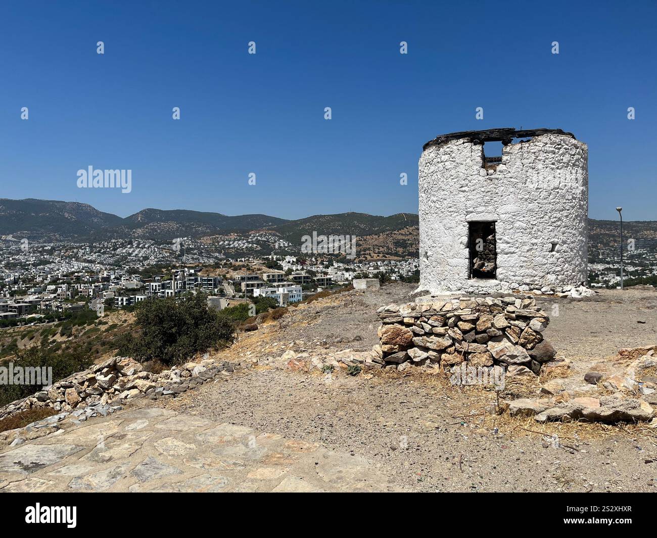 The old mill in the background of the city Bodrum panorama with mountains and white houses. Blue sky, no clouds - Smartphone Captured Stock Image
