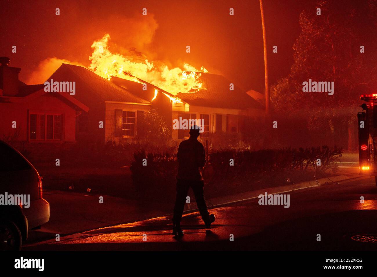 A firefighter walks toward a burning structure as the Eaton Fire