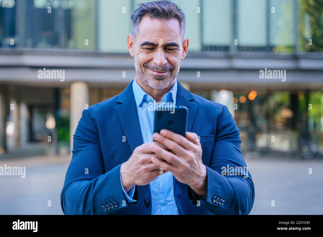 Confident businessman using smartphone outdoors Stock Photo