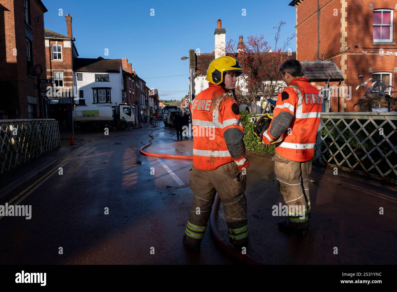 Emergency services attend the scene as people in the Worcestershire town of Tenbury Wells clean up silt and mud following flooding during Storm Bert on 25th November 2024 in Tenbury Wells, United Kingdom. As heavy rainfall from Storm Bert impacted right across the UK, the town of Tenbury Wells flooded after river levels at Kyre Brook rose, causing a wall to collapse on Market Street allowing flood waters to fill the town, inundating properties. Further damage was caused by a tractor being driven through the flooded streets causing a wave which broke windows in local businesses. Stock Photo