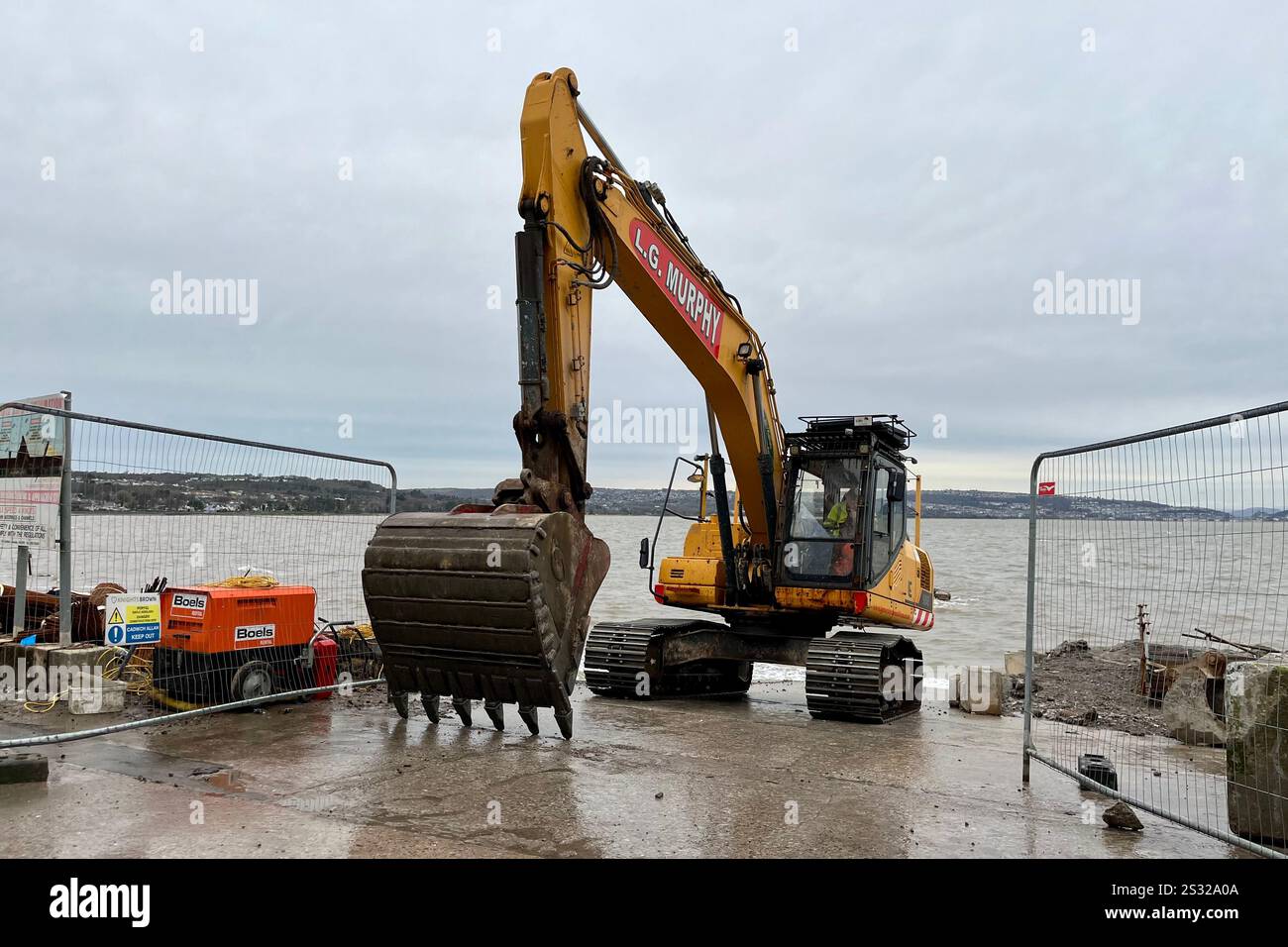 A Yellow Excavator of the Mumbles Coastal Protection Project seen at Southend. Mumbles, Swansea, Wales, United Kingdom. 8th January 2025. - Smartphone Captured Stock Image