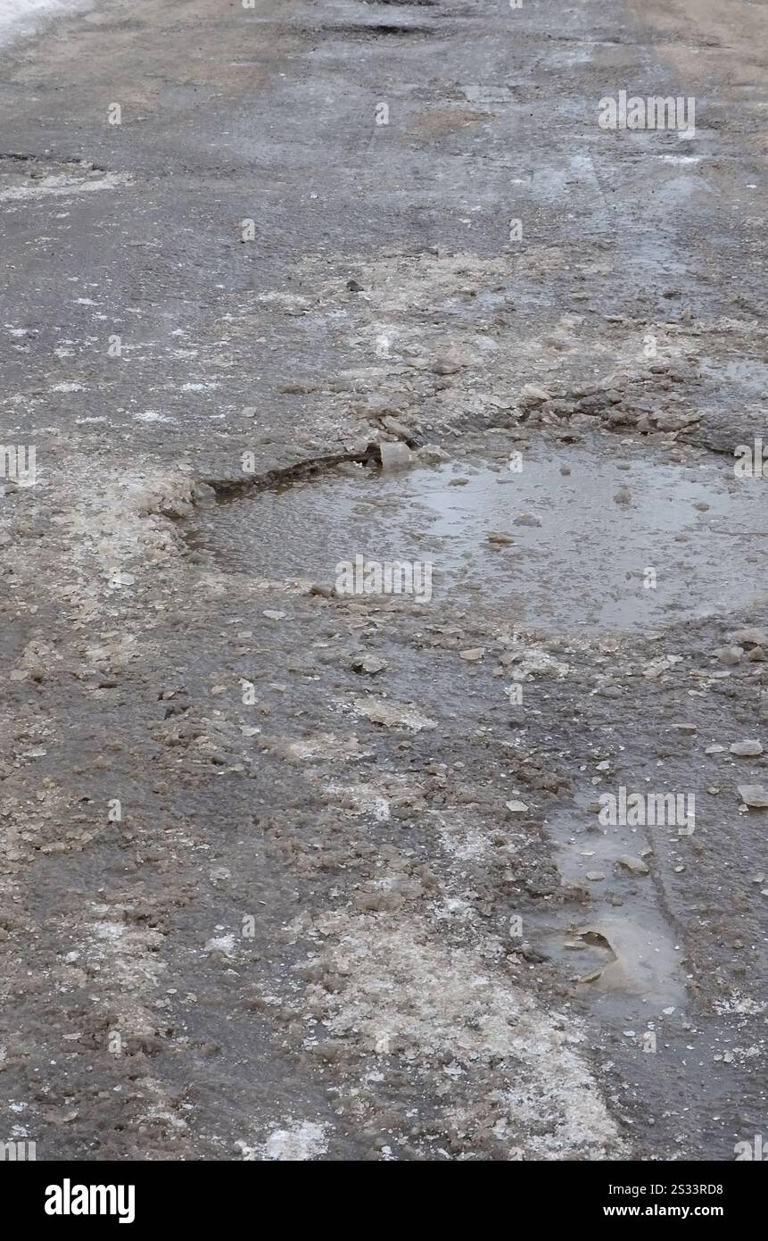 Freezing Roard Condition Damaged asphalt road with potholes caused by freezing and thawing ...