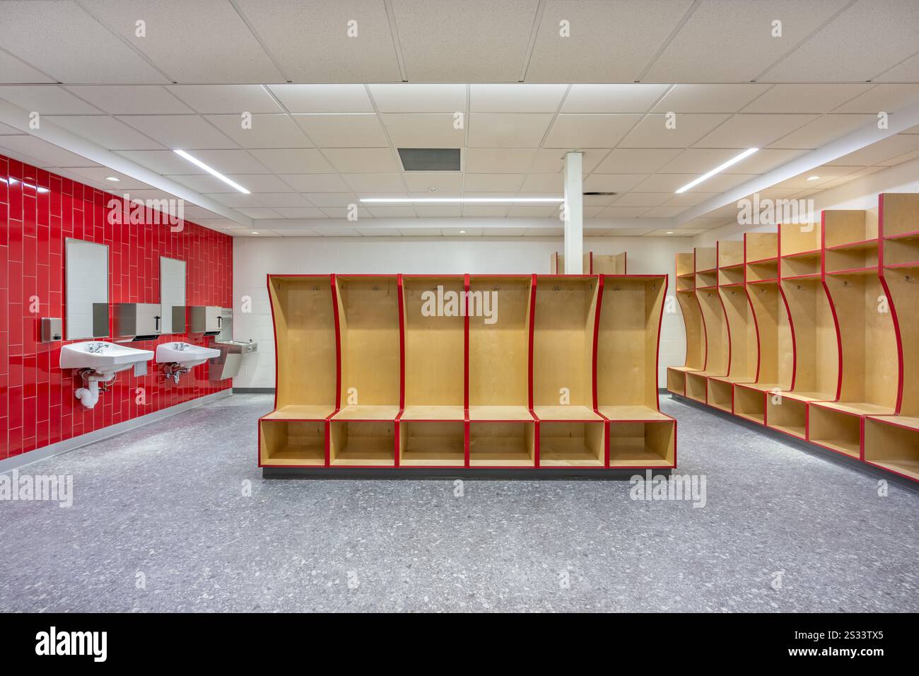 Empty team locker, changing room with traditional open wooden lockers with a red trim. Stock Photo