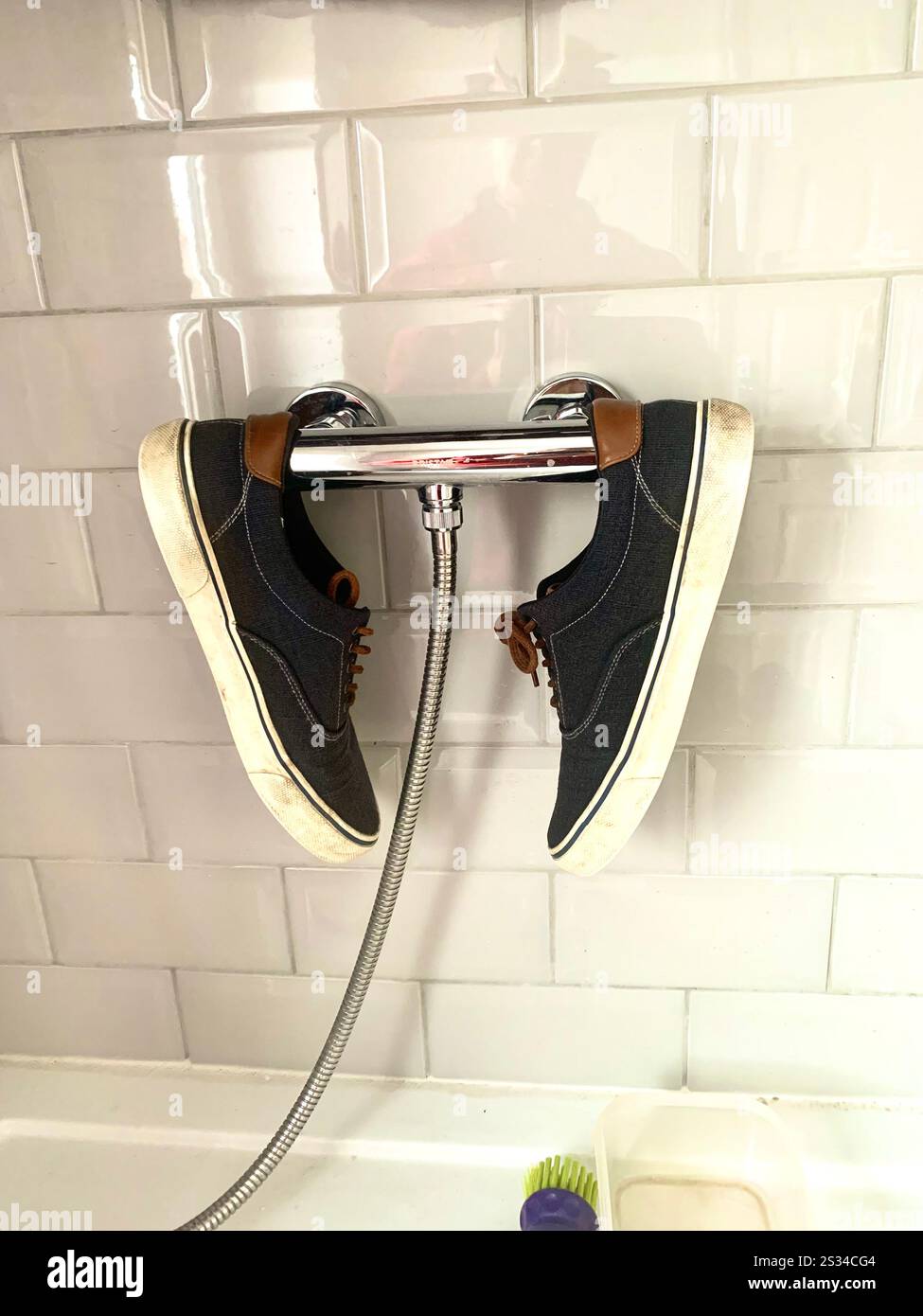 Black shoes drying in bathroom on a rail silver cloth canvas style type Mens men ladies lady grey tiles shinny reflected reflect reflection daytime UK - Smartphone Captured Stock Image
