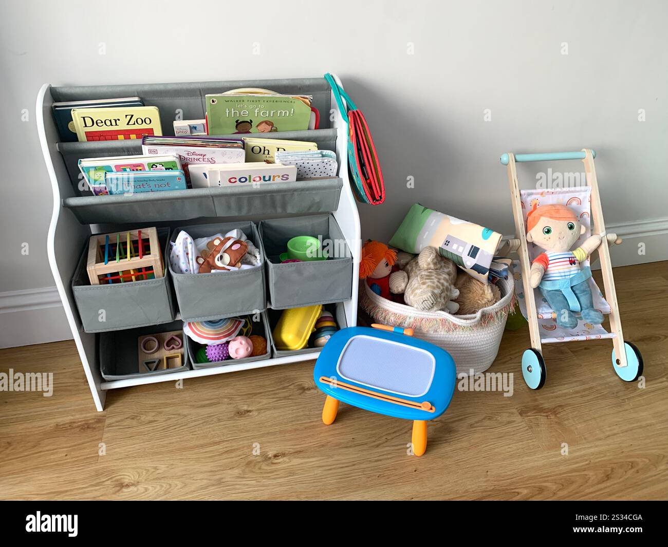 Childs doll and push chair play thing toy books reading cupboard inside toy baby play thing things trolley wheels push pram toy toys games drawing UK - Smartphone Captured Stock Image