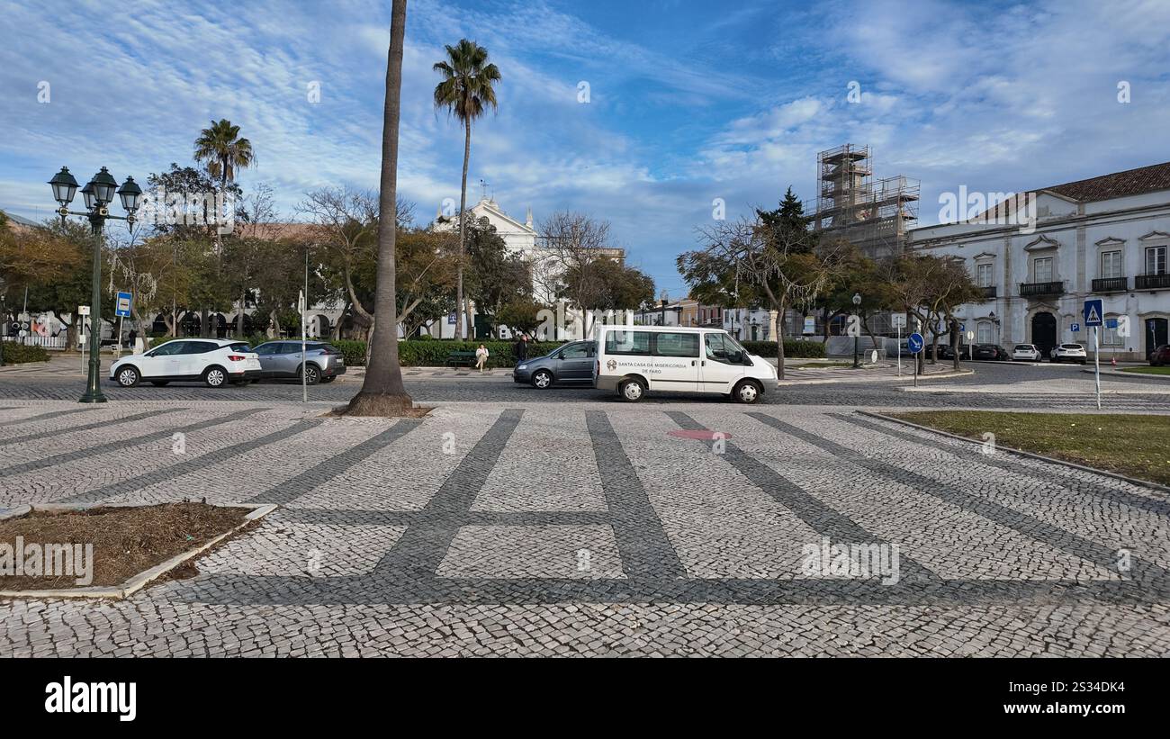 A cobbled stone street with cars on the road in the background, situated in the city center of Faro, Portugal, blending historic charm with modern urb Stock Photo