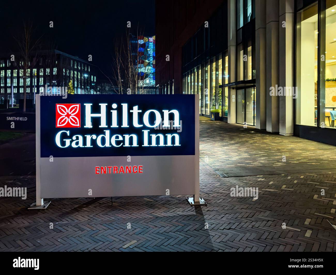 Illuminated sign of Hilton Garden Inn hotel entrance at night outside a modern building with large windows - Hanley stoke on trent - Smartphone Captured Stock Image