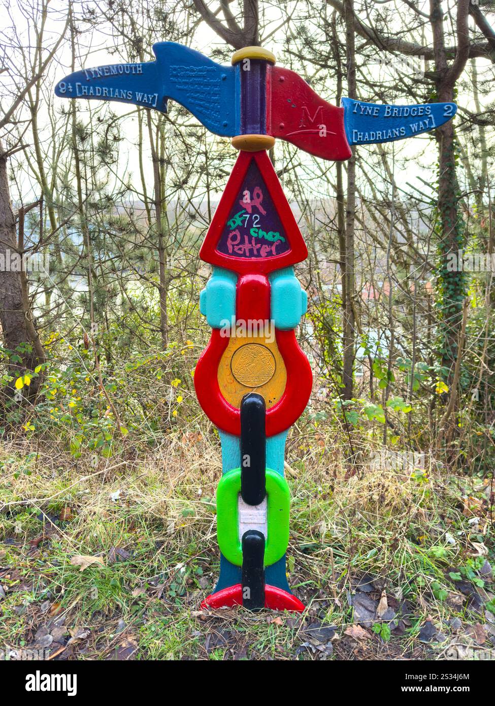 Colourful Trail marker signpost on Hadrians Way with lush greenery in background and playful graffiti detail, walker, river tyne, newcastle uk - Smartphone Captured Stock Image