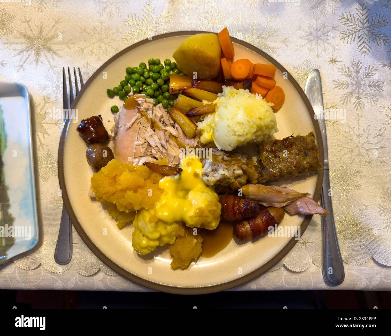 A delicious and colorful Christmas dinner plate with turkey, stuffing, mashed potatoes, and various vegetables on a festive tablecloth - Smartphone Captured Stock Image