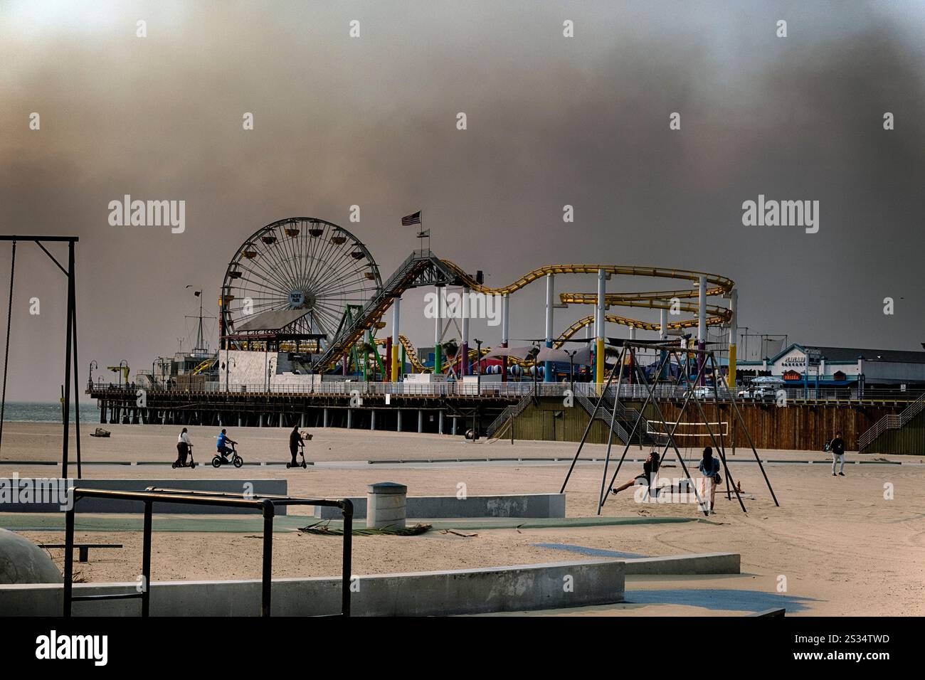 People play on the beach as smoke from a wildfire blows over the Santa