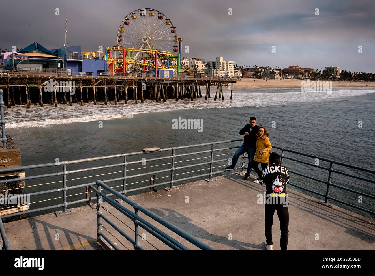Tourists take photos from the Santa Monica pier as heavy smoke from a