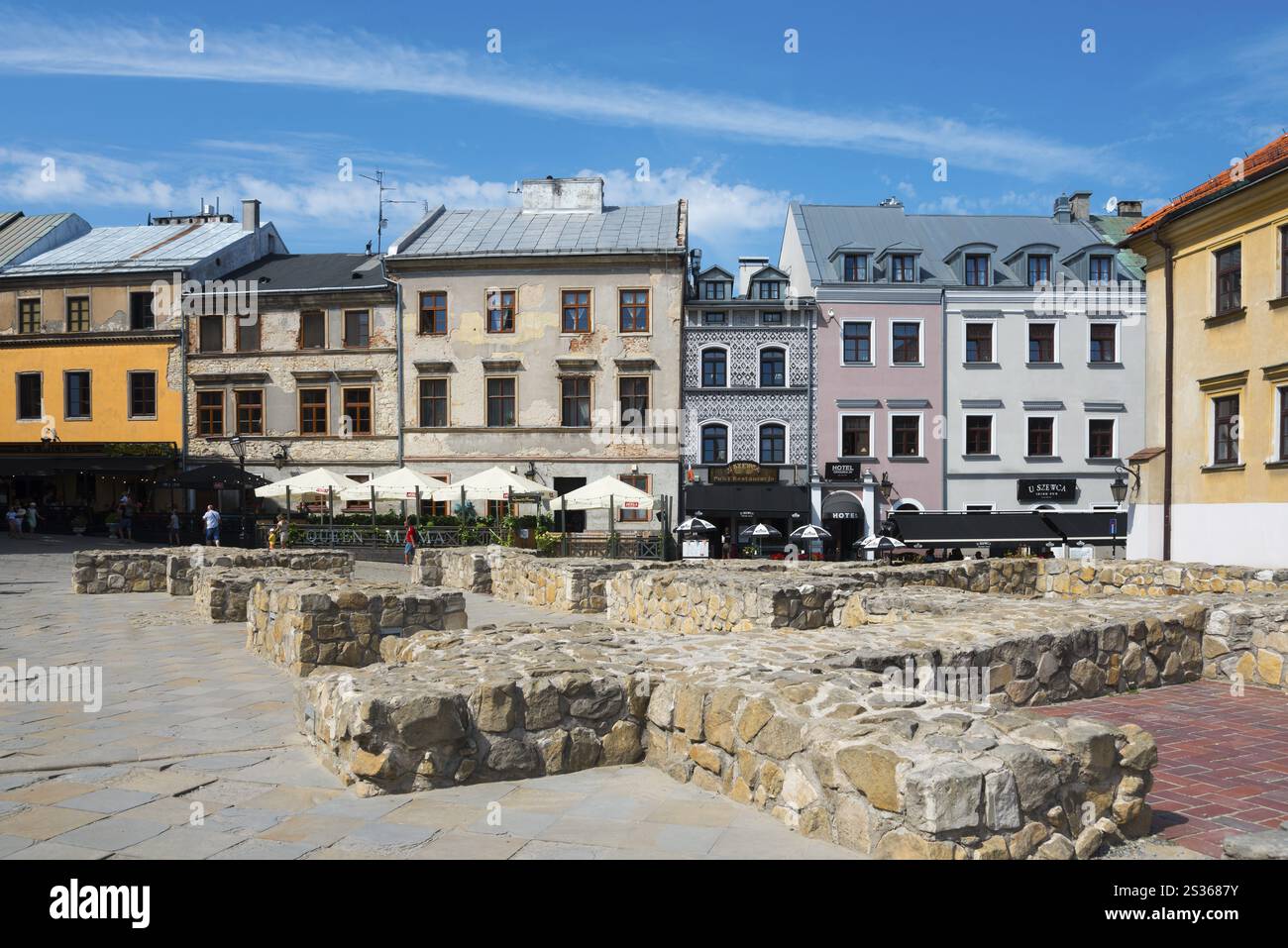 Row of historic houses and stone benches on a sunny square, foundations of St Michael's parish church and houses on Grodzka Street, Lublin, Poland, Eu Stock Photo