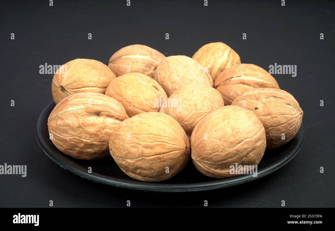 One full plate of dry walnut in black background Stock Photo