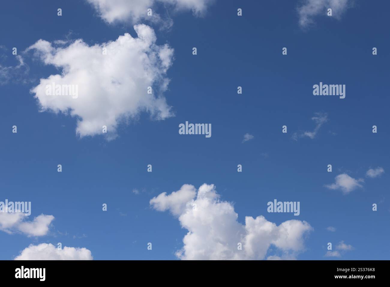 white puffy clouds floating against deep blue skies Stock Photo