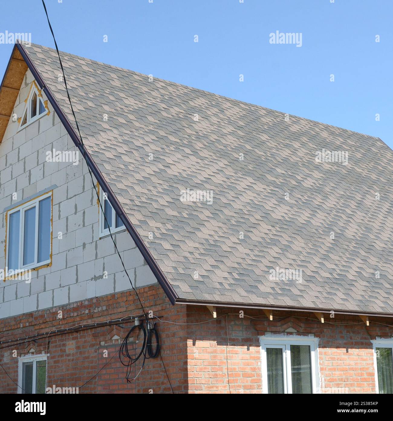 Bricks Bitumen Flexible shingles of bitumen roofing surface on the brick house. Mosaic ...