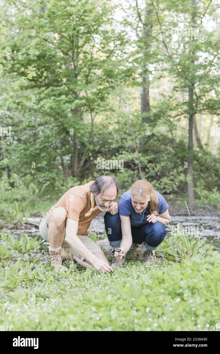 Two biologists crouching in retiro park, madrid, examining plants with ...
