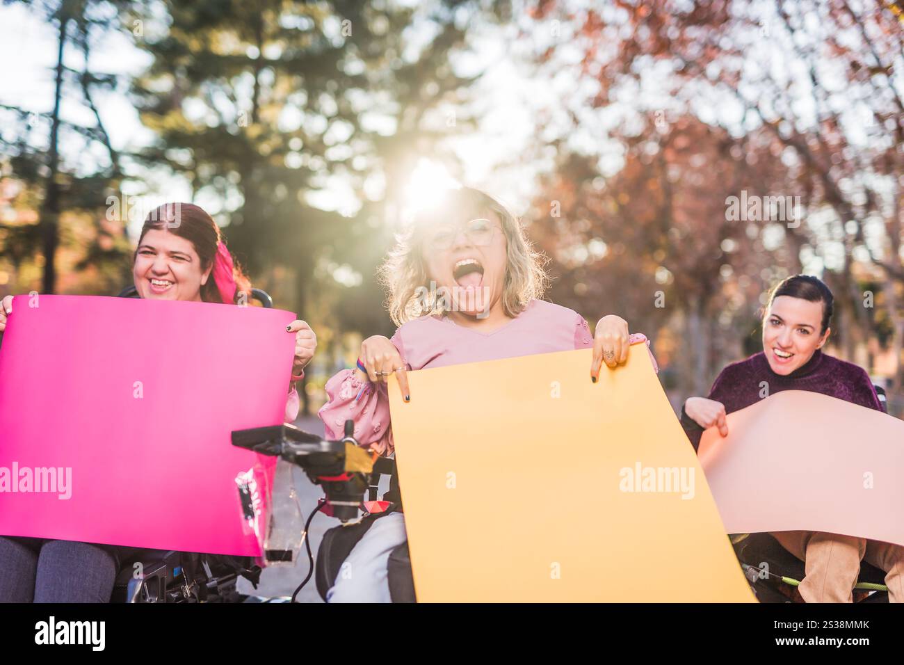 Smiling women with cerebral palsy showing colorful placards at protest ...