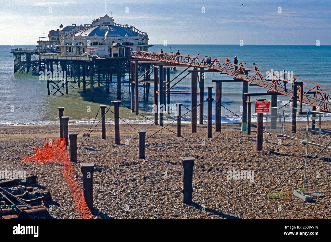 Brighton’s West Pier photographed from The Esplanade, Brighton, East Sussex, England, UK in 1996. The pier, designed by Eugenius Birch, was built in 1866. It has been closed and deteriorating since 1975 – after two fires and several storms, little was left of the structure. A break was caused by high winds in 1987, but the tours of it were made via the walkway shown in the photograph. It suffered a collapse during in 2002, when the walkway connecting the concert hall and pavilion fell into the sea. In 2003 a further collapse saw the destruction of the concert hall. Stock Photo
