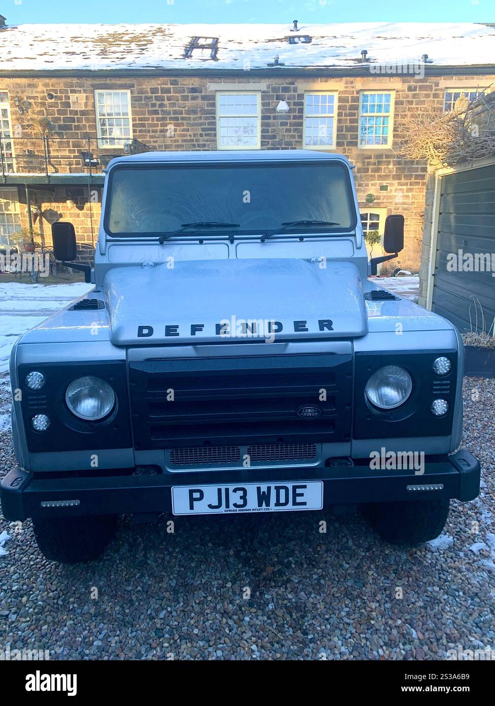 Defender Land rover in Berley in Burley in Wharfedale North Yorkshire number plate silver van car vehicle outside in the snow weather conditions - Smartphone Captured Stock Image