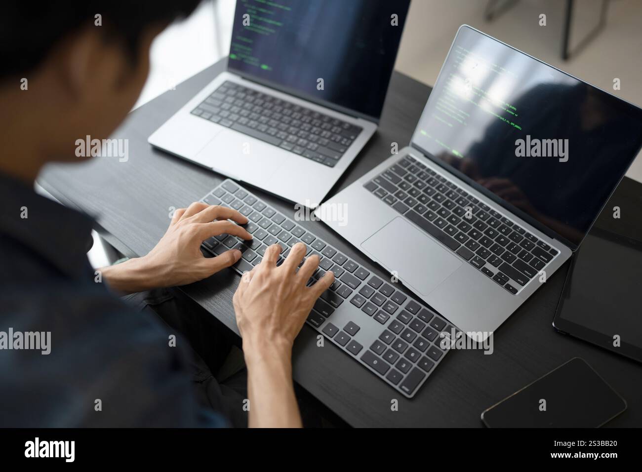 Asian man software engineer Working on Computer at office desk for writing program code IT Software Engineer finding errors tech support devops Stock Photo