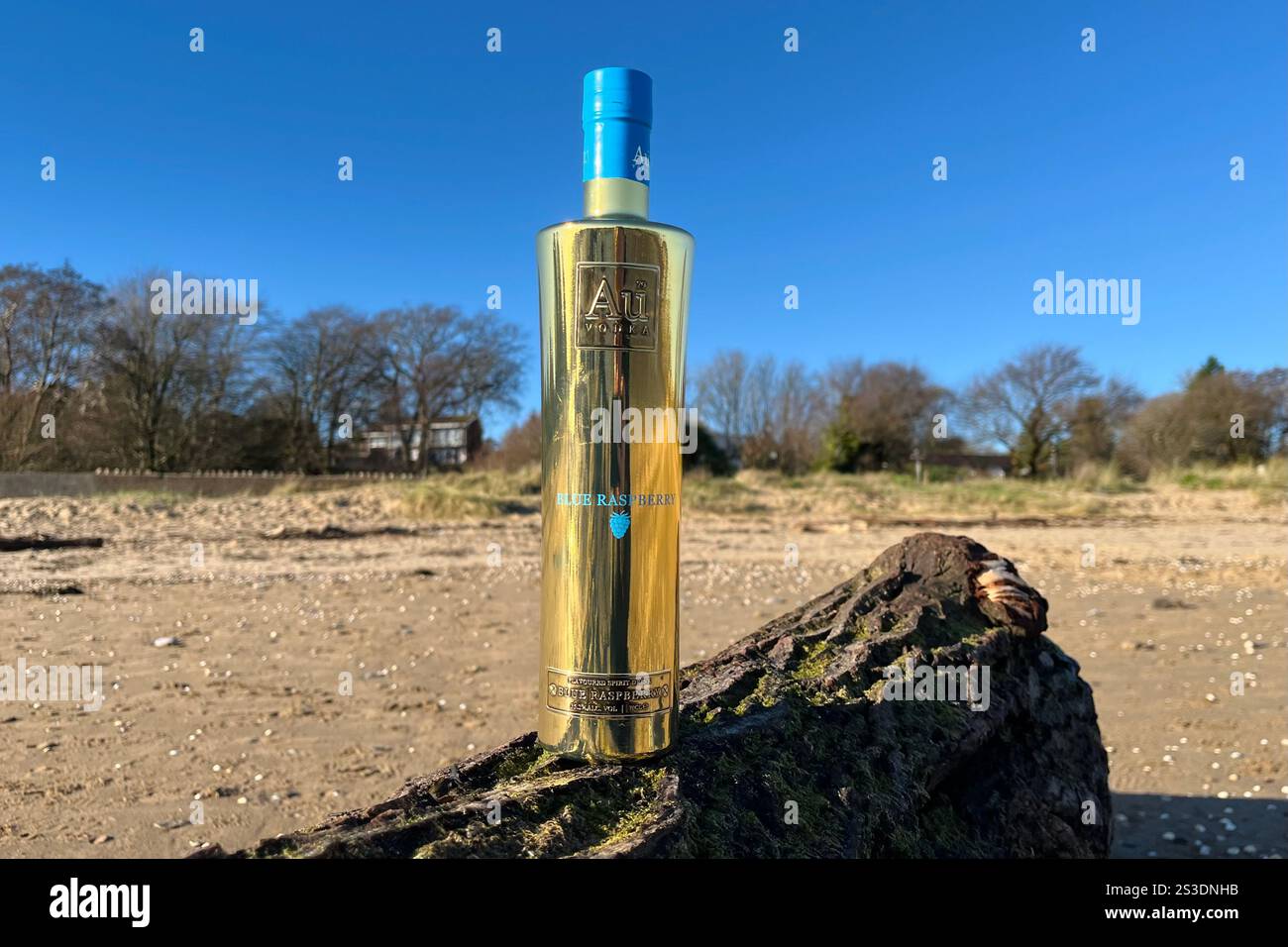 Au Vodka Blue Raspberry 70cl Bottle on Swansea Bay. The Swansea-based company is known for their iconic gold bottles and ultra-premium vodka. Stock Photo