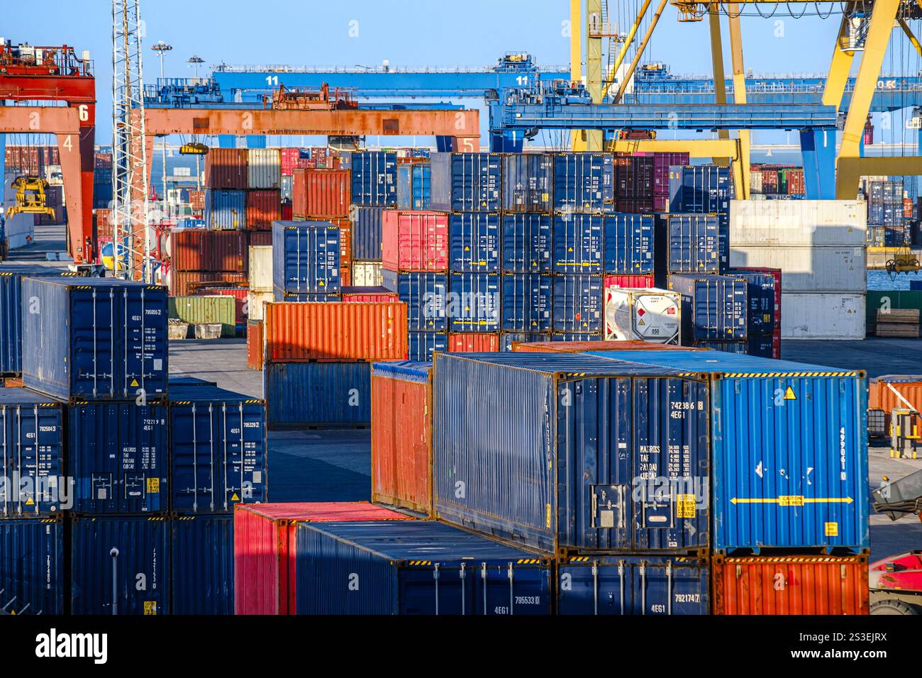 A lot of cargo containers stacked in shipping port under clear blue ...