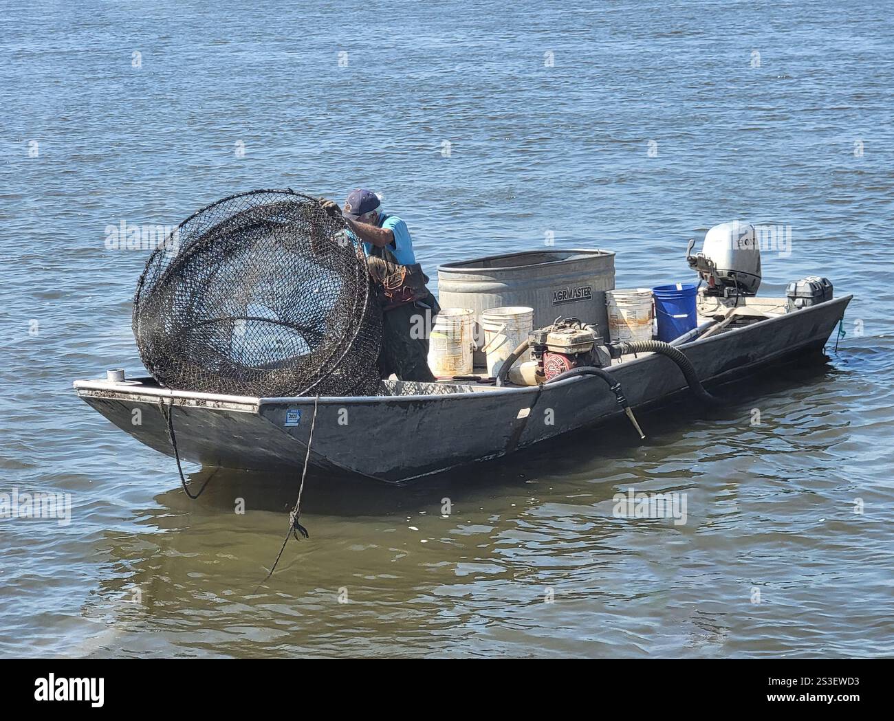 Elderly man fishing with a net on the Mississippi River at Muscatine, Iowa - Smartphone Captured Stock Image